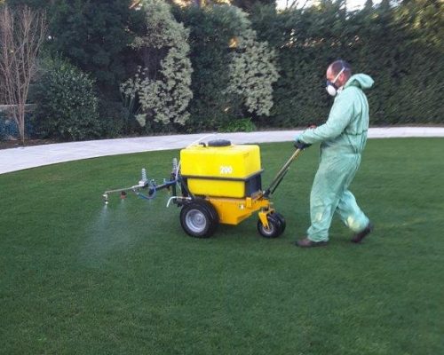 Un technicien répand un traitement sur du gazon